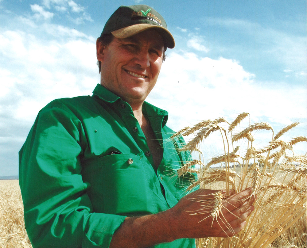 Angus is holding a bunch of his wheat and looking very proud