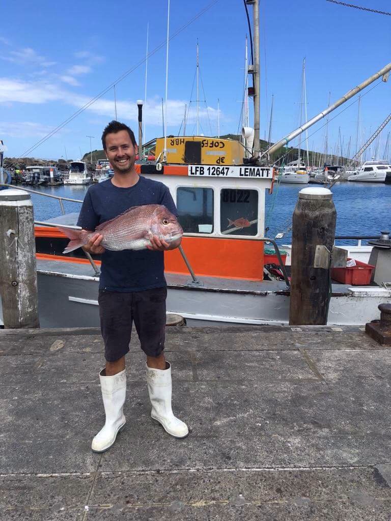 Danny is standing on the warf and holding a good sized snapper