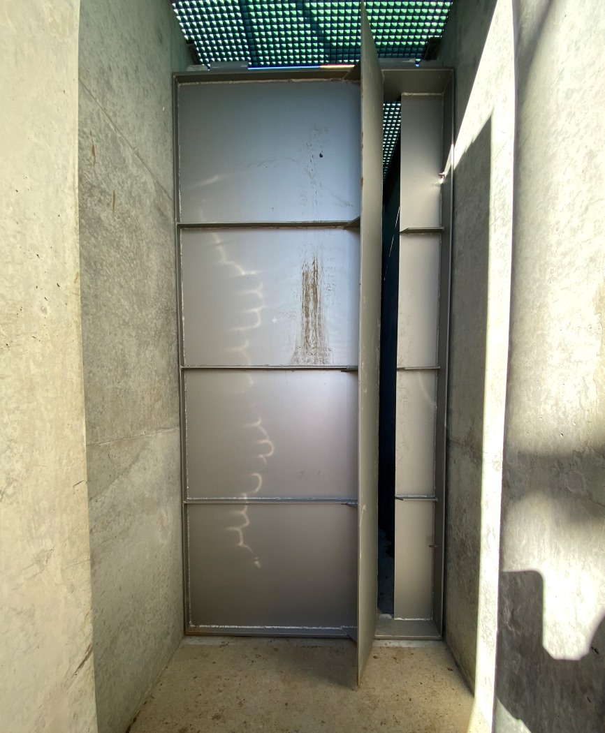 A large metal baffle with vertical slot within the fishway channel.