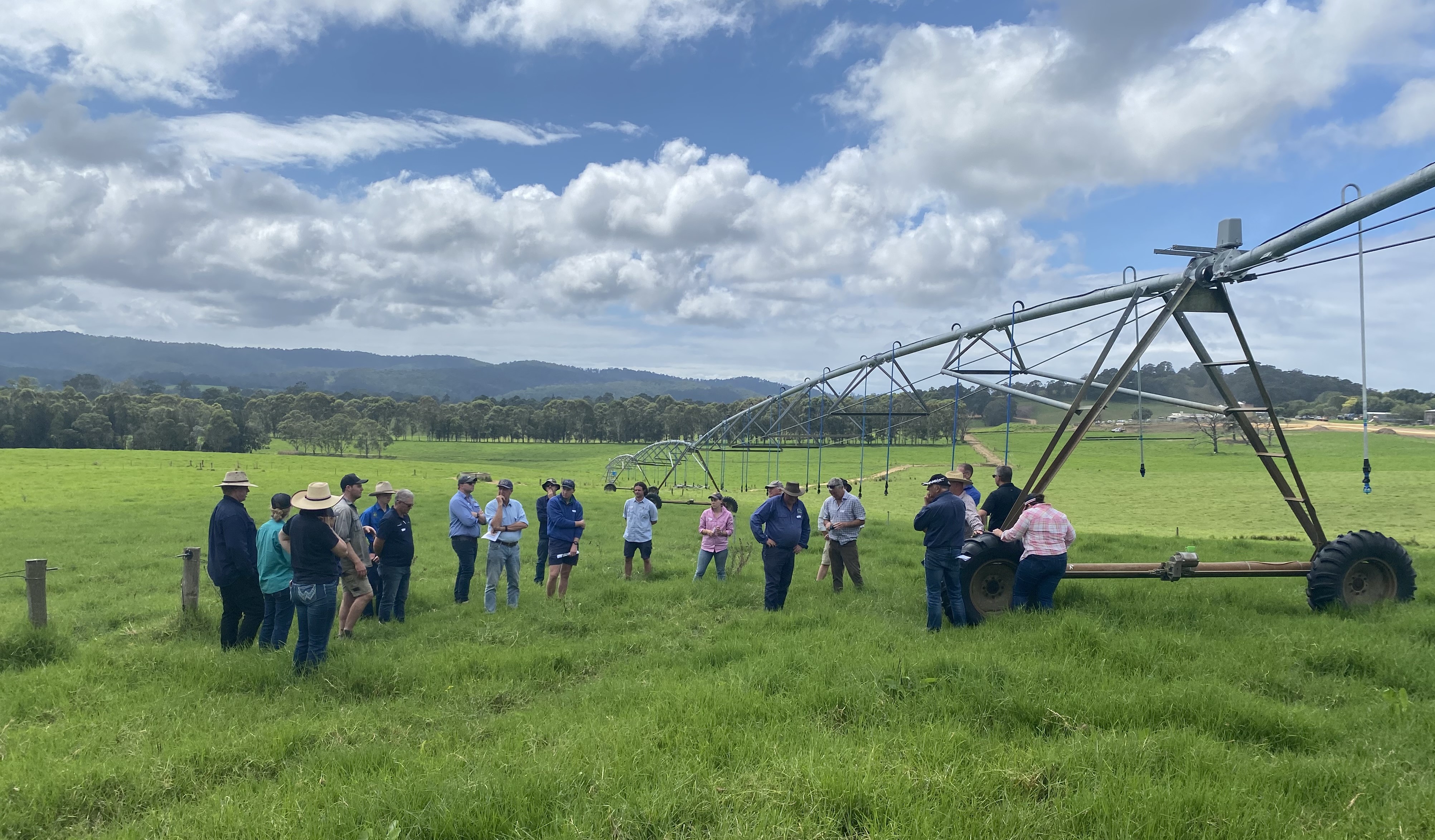 About 20 field day participants inspect a large pivot irrigation machine in a lush grassy paddock.