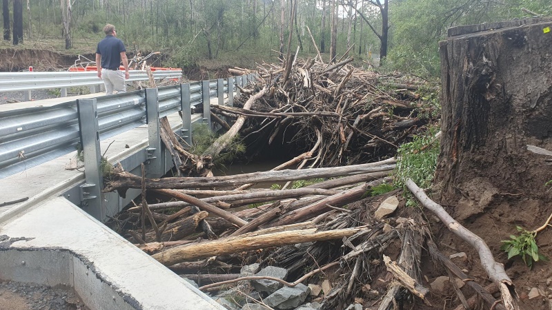 A bridge with tree branch flood debris partially blocking fish passage