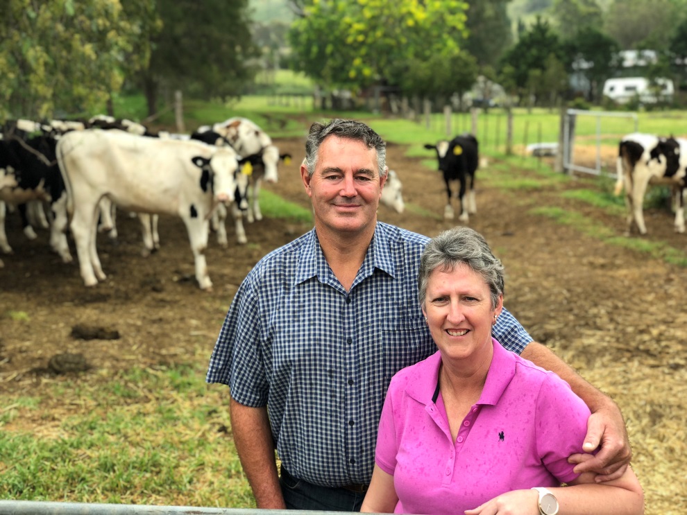 Gavin and Karina are standing near a gate with their cattle behind them