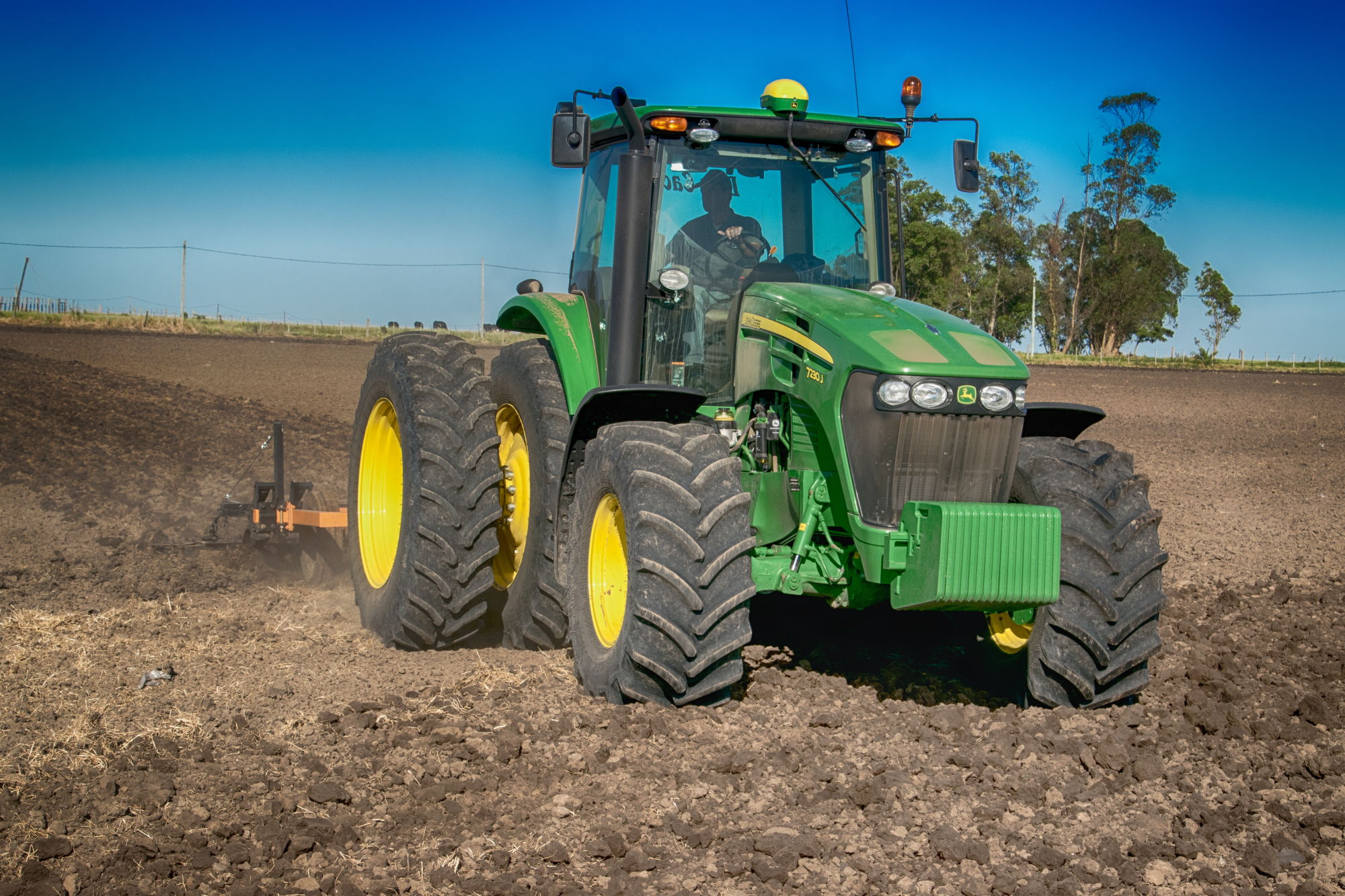 green tractor ploughing farm field