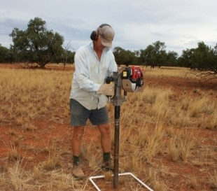 Person taking soil sample from quadrat with hand held pneumatic corer
