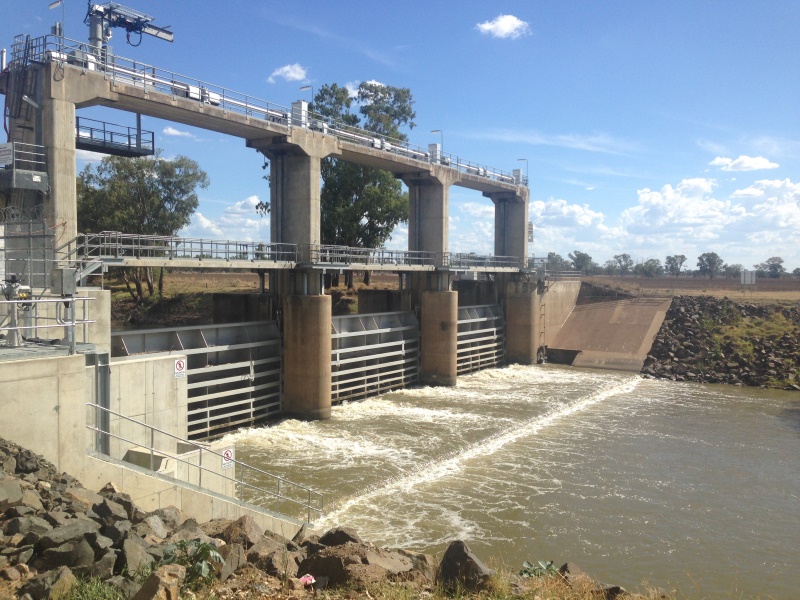 A large gated weir extends across the river channel and blocks fish passage.