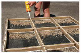 A farmer applying lines of silicon to an oyster tray