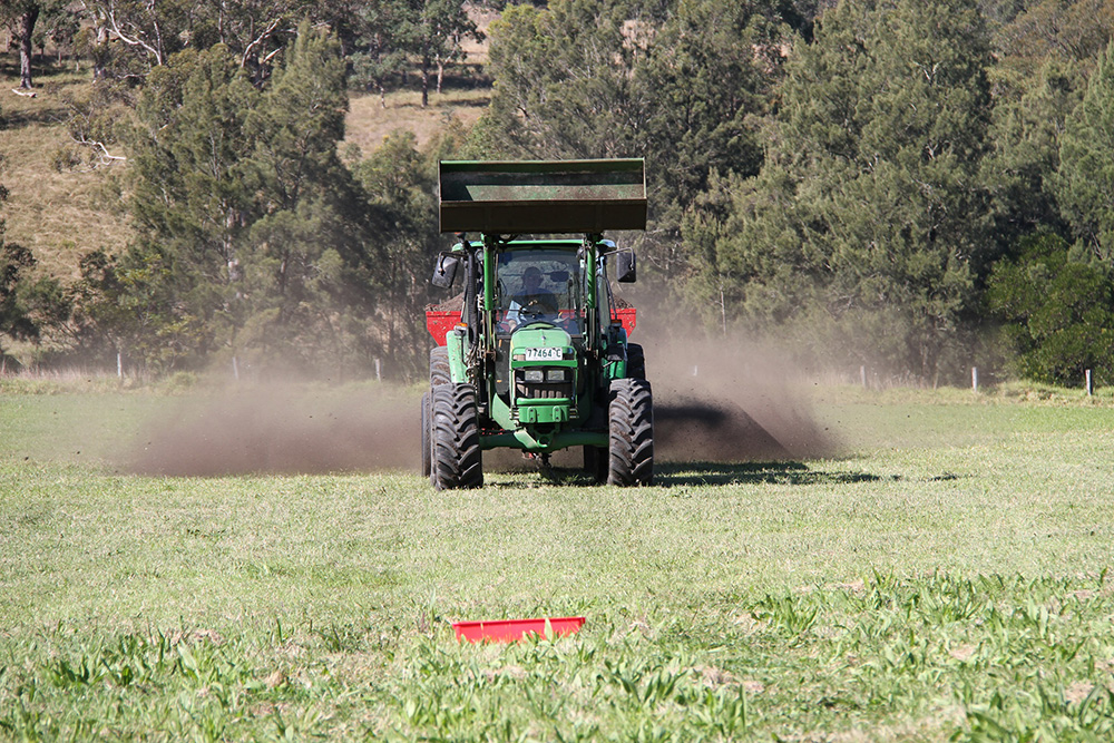 A tractor in a paddock spreading fertiliser