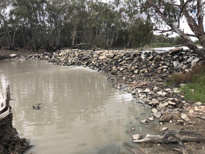 A low rock weir extends across the river channel.