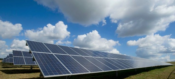 Solar panels in field with sun sky clouds