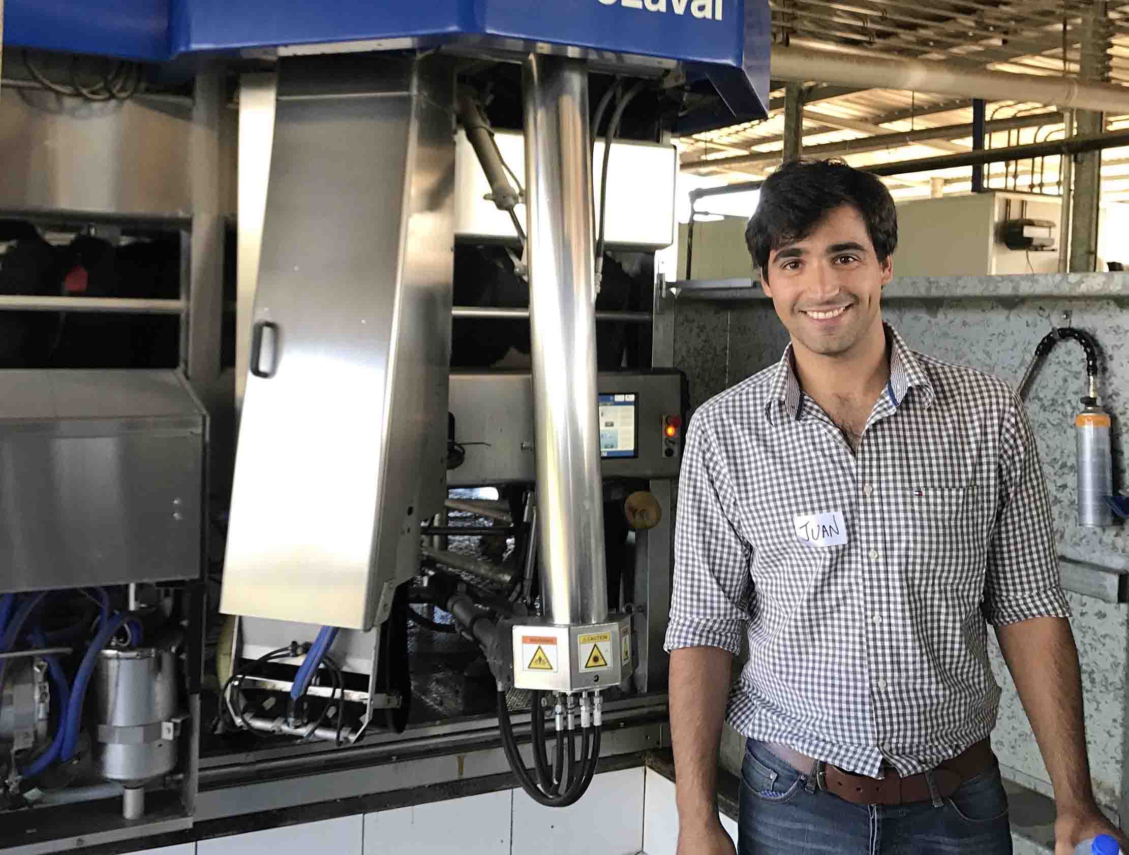 Dr Juan Gargiulo standing in front of an automated milking machine.