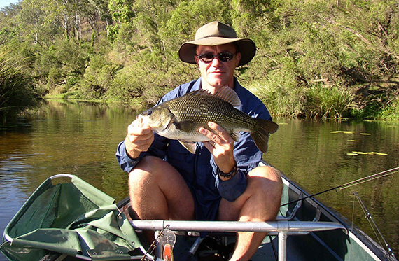 Bass fisherman with Australian Bass and good vegetated bank