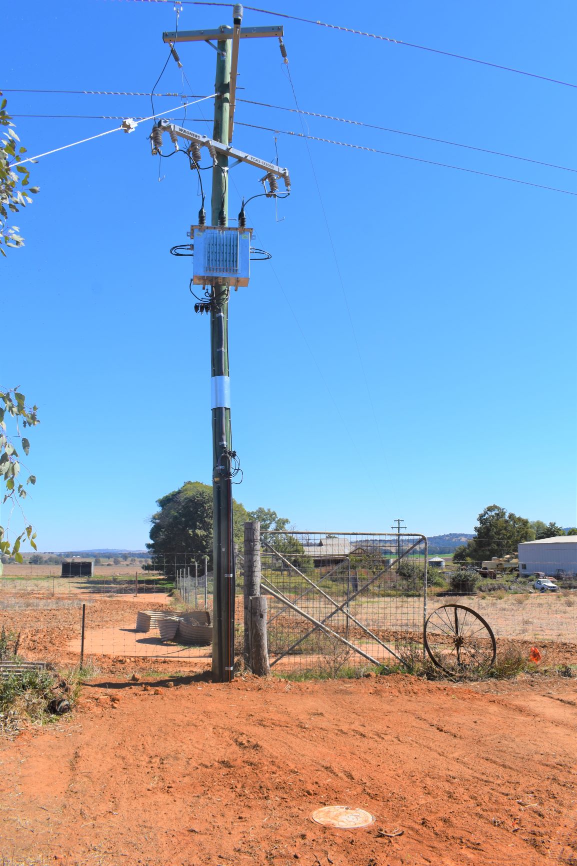 electricity power pole on farm red soil and fence gate and wagon wheel