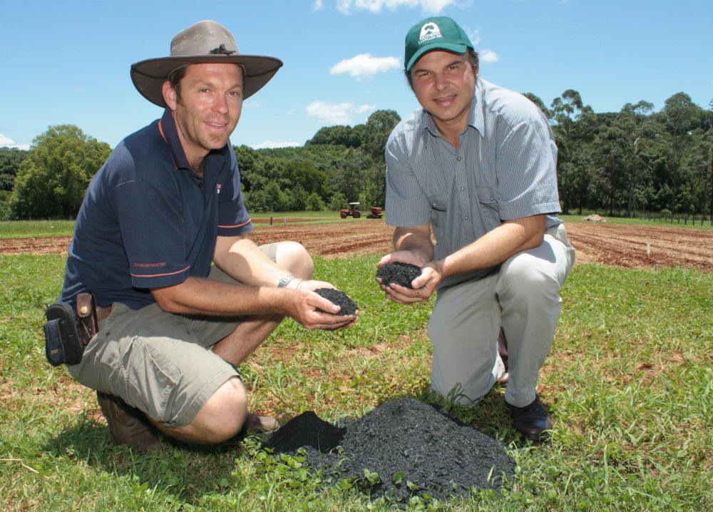 Drs Van Zwieten and Singh are holding handfuls of soil and smiling towards the camera