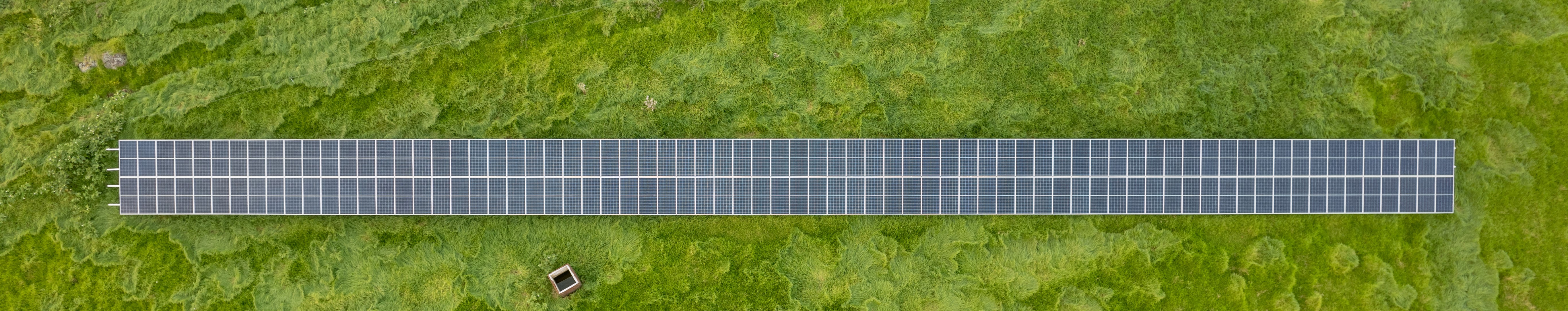 drone photo looking down on solar panels on bright green pasture