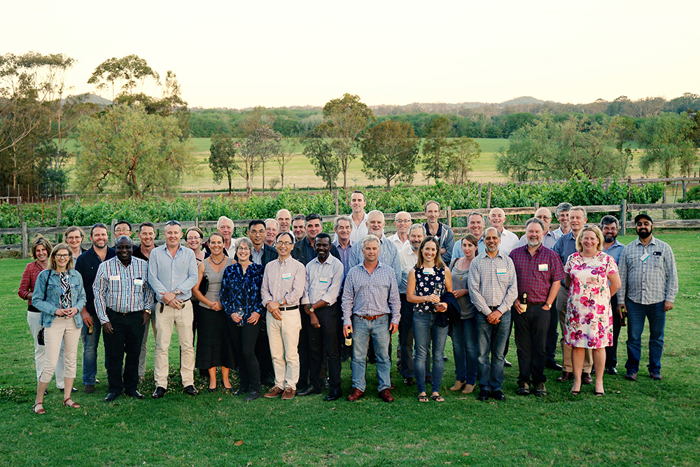 All participants are group in front of a vineyard and smiling to the camera